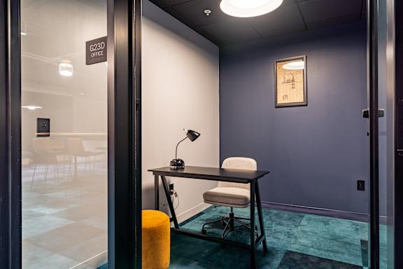 a desk with a chair and a lamp in a room with a door
