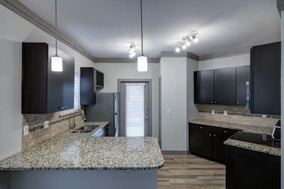 A kitchen with granite countertops and black cabinets.