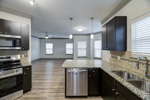 A kitchen with black cabinets and a granite peninsula countertop at Adara Overland Park.