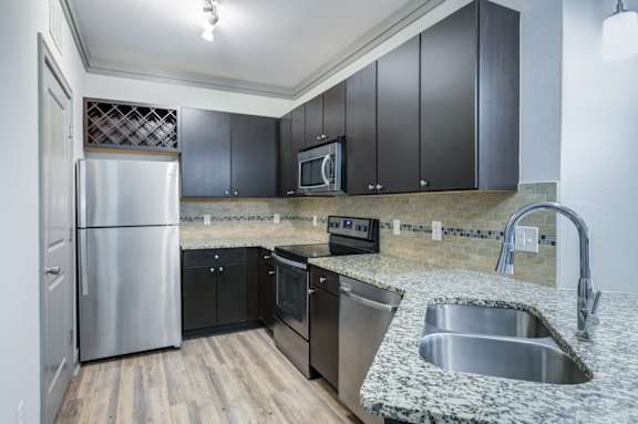 A kitchen with a stainless steel refrigerator, oven, and sink.