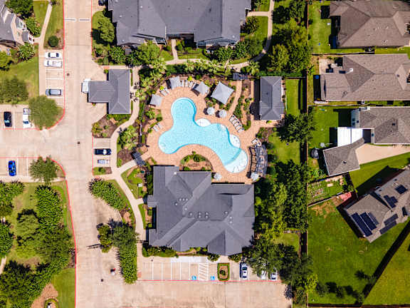A bird's eye view of a neighborhood with a swimming pool in the center at Avenues at Shadow Creek Ranch Apartments, Pearland, TX, 77584