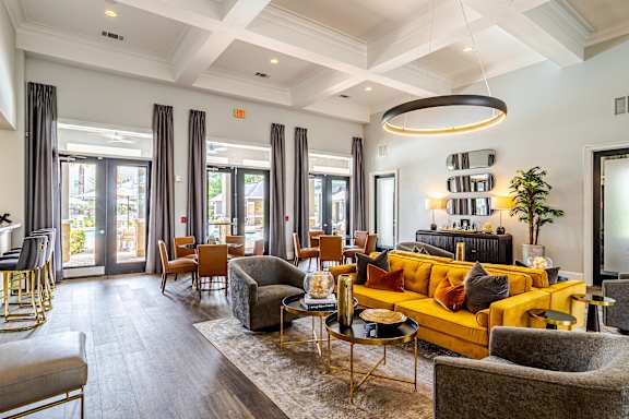 A modern living room with a yellow sofa and wooden floors at Avenues at Shadow Creek Ranch Apartments, Pearland, Texas