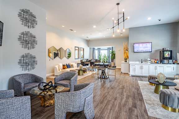 A modern living room with grey chairs and a white sofa at Avenues at Shadow Creek Ranch Apartments, Pearland, TX