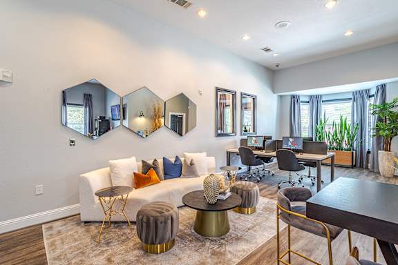 A modern living room with a white couch, a coffee table, and a large mirror on the wall at Avenues at Shadow Creek Ranch Apartments, Pearland, TX, 77584