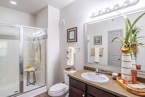 A bathroom with a toilet, sink, and mirror at Avenues at Shadow Creek Ranch Apartments, Pearland
