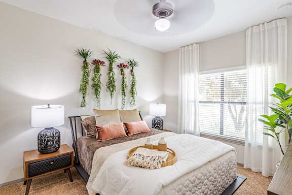 A bedroom with a bed, nightstands, and a window at Avenues at Shadow Creek Ranch Apartments, Pearland, Texas