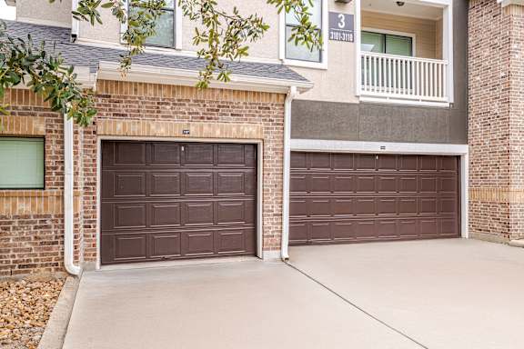 Two brown garage doors in front of a brick building at Avenues at Shadow Creek Ranch Apartments, Pearland