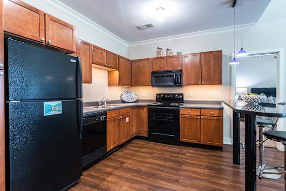 A kitchen with wooden cabinets and black appliances. at CityView, North Kansas City