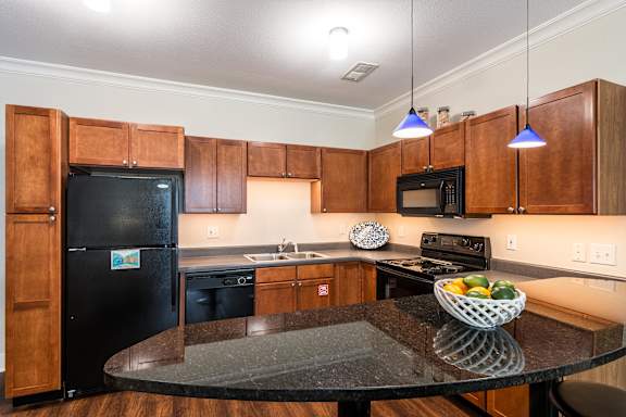 A kitchen with wooden cabinets and a black fridge. at CityView, North Kansas City