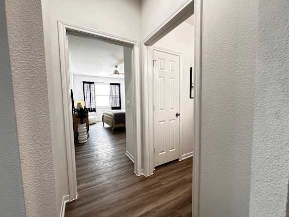 A white door is open to a room with a bed and a plant at Grand Villas Apartments, Katy