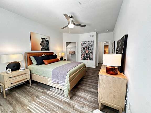 A bedroom with a bed, nightstand, and a ceiling fan.
