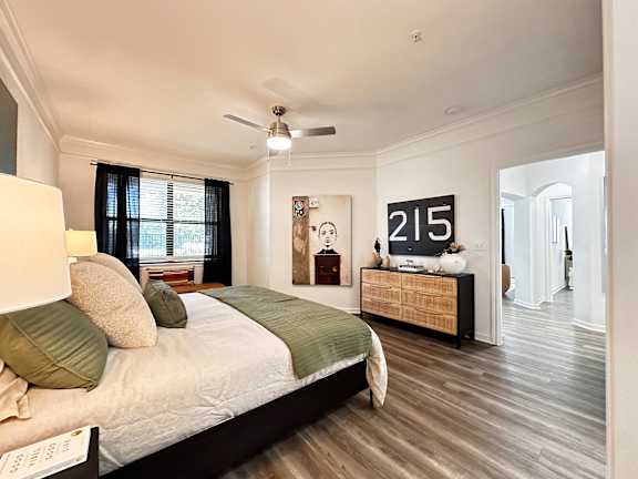 A bedroom with a bed, dresser, and a ceiling fan at Grand Villas Apartments, Katy