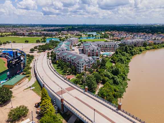 Bridge over a river with a road and buildings on both sides at Imperial Lofts, Sugar Land, 77498