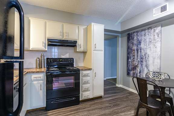 A kitchen with a black refrigerator and black oven. at London House Apartments, Lenexa
