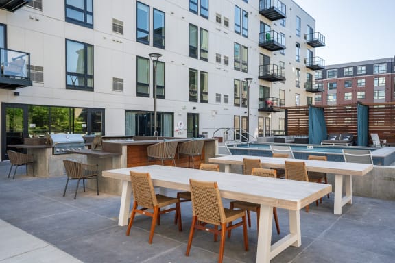 an outdoor patio with tables and chairs and a pool in front of an apartment building at Marquee, Minneapolis, MN