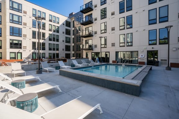 a pool with lounge chairs in front of an apartment building at Marquee, Minnesota, 55403