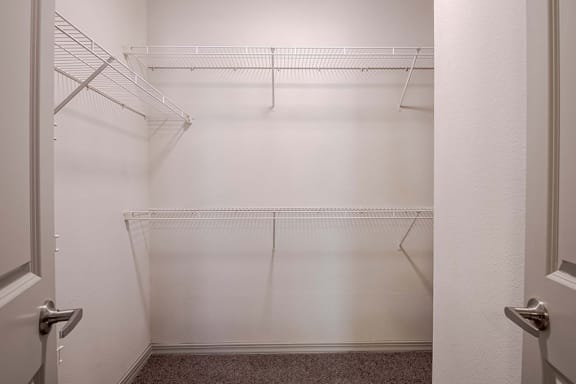 a walk in closet with empty shelves in a white room at Discovery at Craig Ranch, McKinney, TX