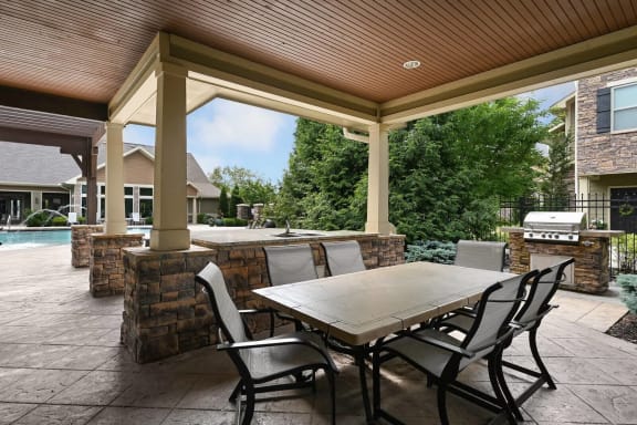 a covered patio with a table and chairs and a pool at Sovereign at Overland Park, Overland Park