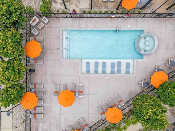 An aerial view of a pool surrounded by orange umbrellas and chairs. at Penn Circle, Indiana, 46032