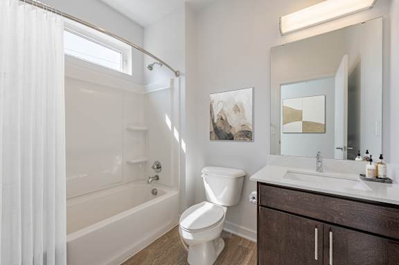A white toilet sits next to a white bathtub in a bathroom. at Pinnex, Indianapolis, IN