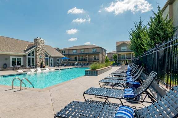 A row of blue and white striped lounge chairs line the edge of a swimming pool.