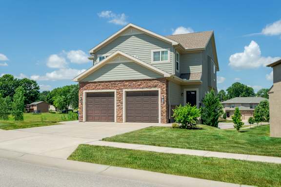 A house with a grey roof and two brown garage doors.