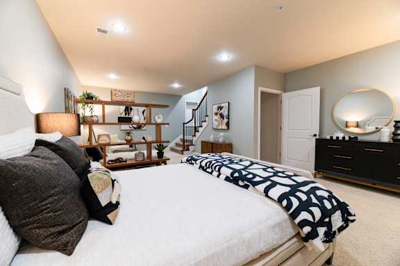 A bedroom with a large bed and a dresser with a mirror.