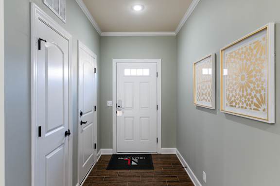 A hallway with a white door and two framed pictures on the wall.