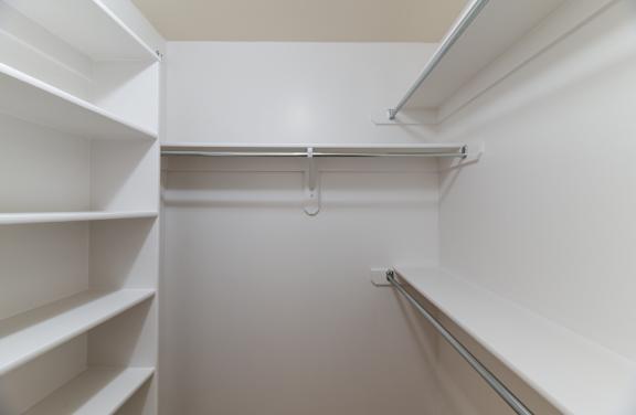 A white pantry with a white door and a white shelf.