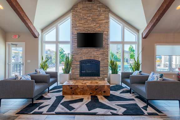 A living room with a stone fireplace and grey couches.