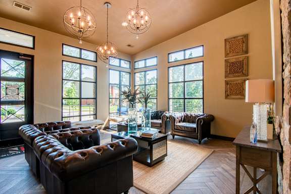 A living room with a long black couch and a glass coffee table.