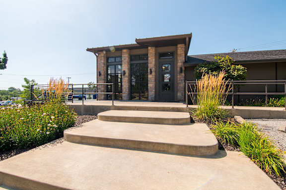 A small building with a concrete staircase leading to a glass door.