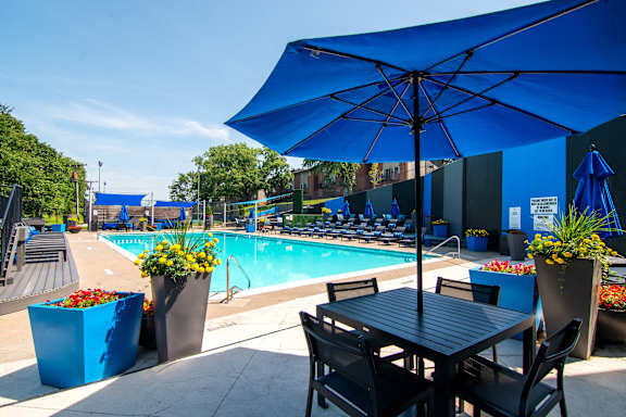 A poolside table with chairs and umbrella overlooking a pool.