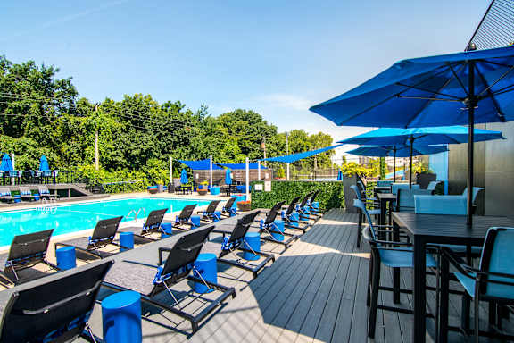 A poolside area with blue umbrellas and chairs.