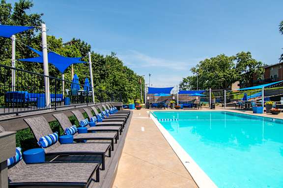 A pool with blue chairs and umbrellas.