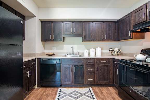 A kitchen with black appliances and wooden cabinets.
