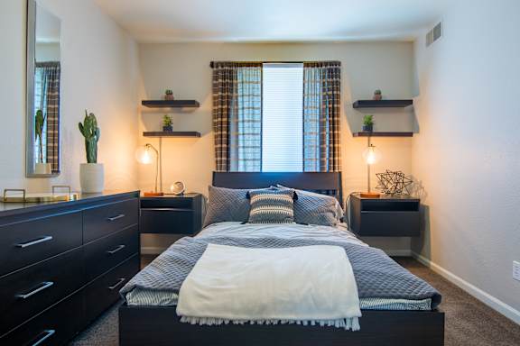 A bedroom with a large bed, a dresser, and a mirror.