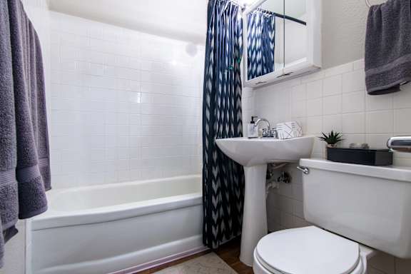 A white sink is in a bathroom with a white toilet and a white bathtub.