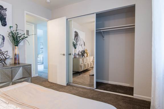 A white bed sits in a bedroom with a mirrored closet door.