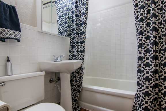 A white sink is in a bathroom with a black and white shower curtain.