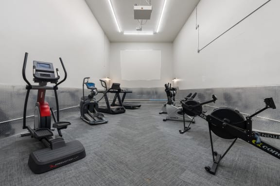 a gym with cardio exercise equipment and a white wall at Candles, Springfield, Illinois