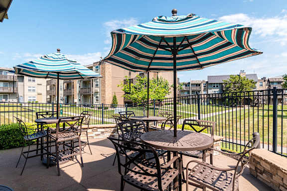 A patio with a table and chairs under a striped umbrella.