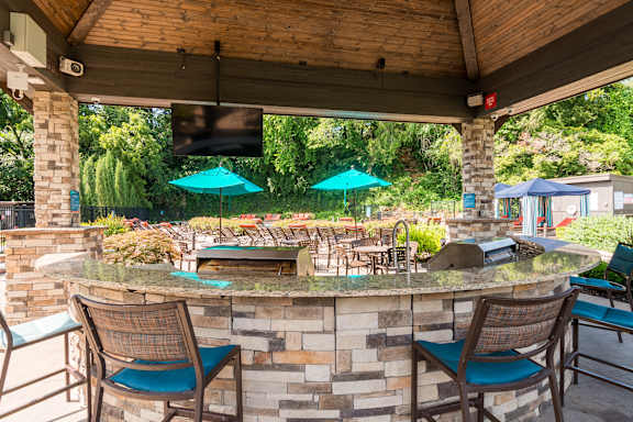 A patio with a bar and chairs under a roof.