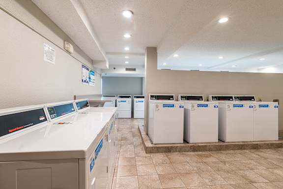 A laundromat with washers and dryers lined up.