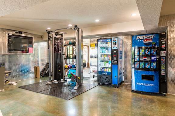 A Pepsi vending machine is in a room with a black mat on the floor.