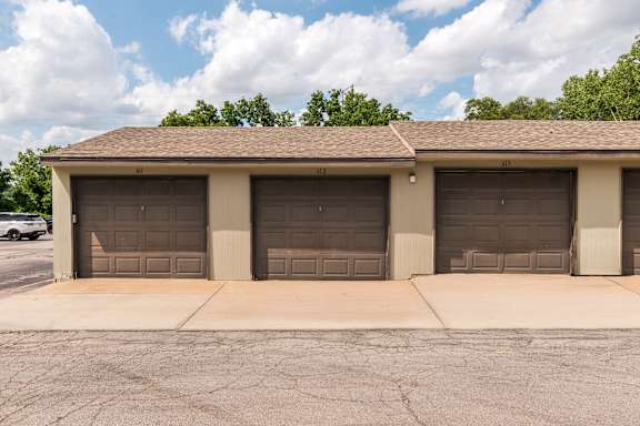 A building with three garage doors is in front of a tree.