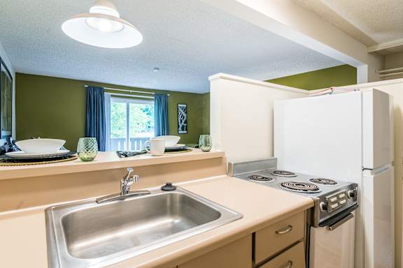 A kitchen with a white refrigerator, stove, and sink.