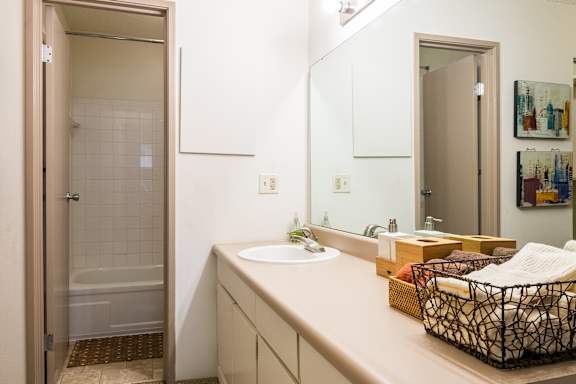 A bathroom with a sink, mirror, and a glass shower stall.