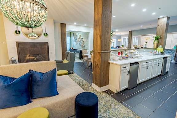 A modern living room with a fireplace and a kitchen area in the background. at The Greyson, Hilliard, OH, 43026