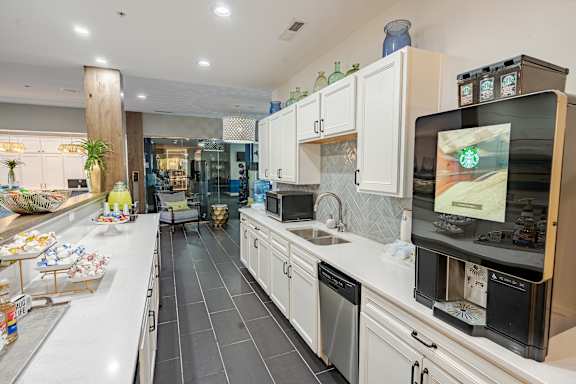 A modern kitchen with a large island and a flat screen TV mounted above the sink. at The Greyson, Hilliard